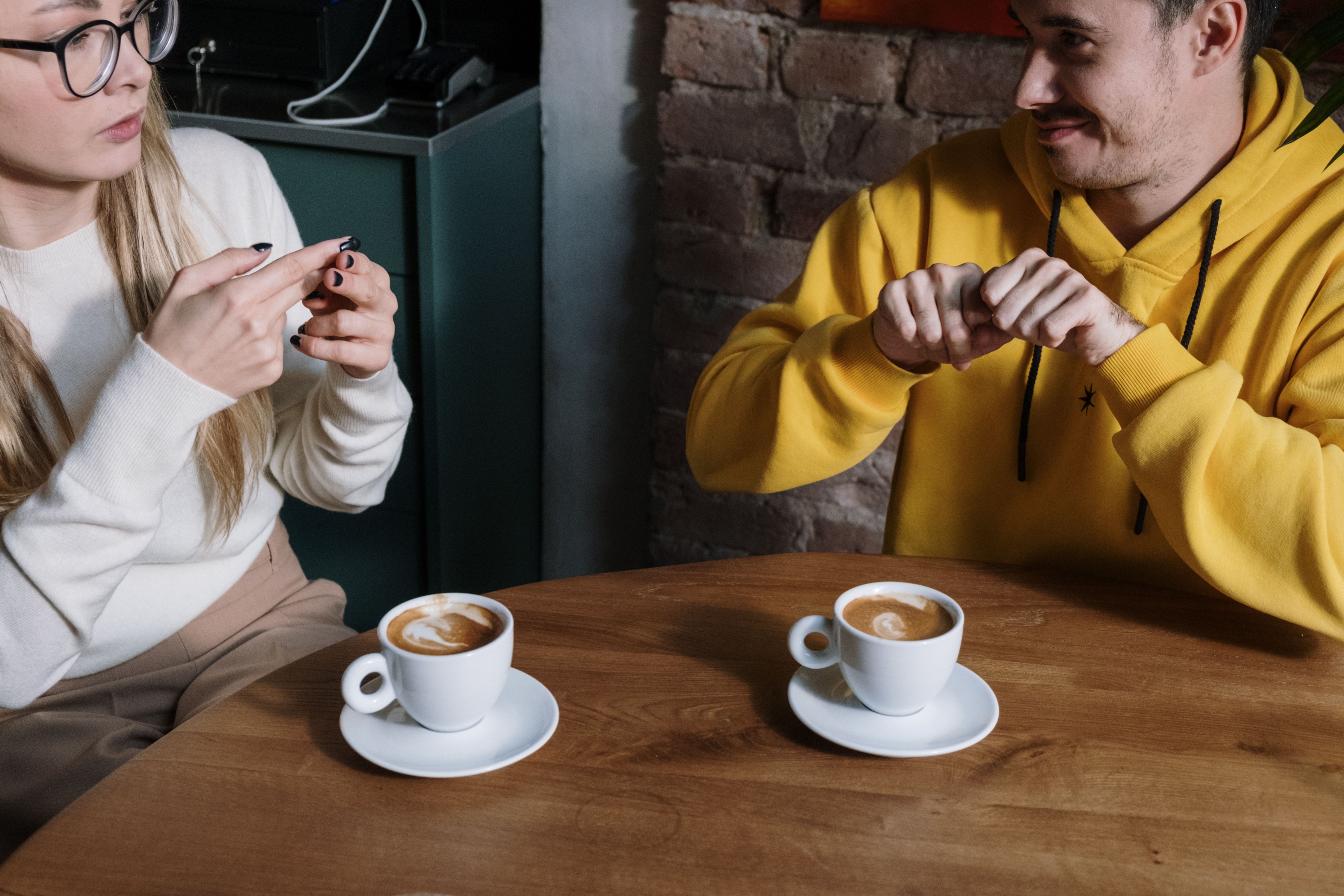 Couple signing and communicating in coffee shop, representing deaf bride meeting Couple signing and communicating in coffee shop, representing deaf bride meeting