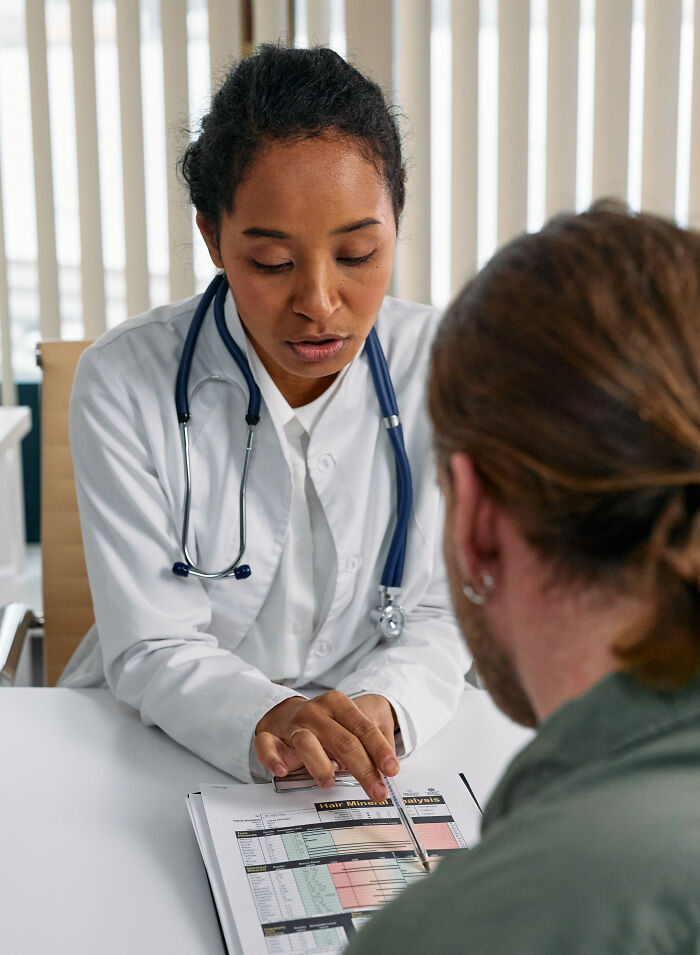 A female doctor discussing health symptoms and medical test results with a male patient, focusing on health symptoms.