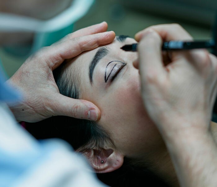 A Japanese woman undergoing cosmetic marking, highlighting Western beauty standards influence. A Japanese woman undergoing cosmetic marking, highlighting Western beauty standards influence.