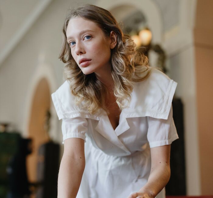 A blonde woman in a white dress looking forward, showcasing the contrast between rich people and having class