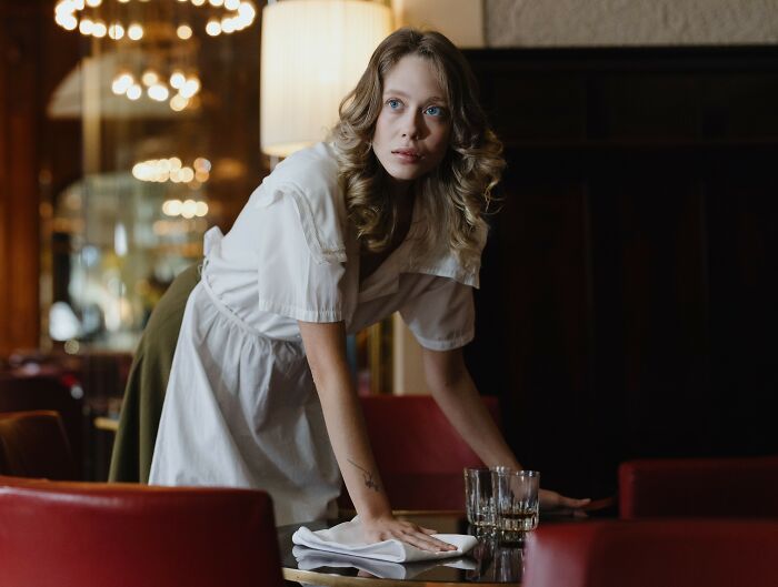 Female waitress cleaning table in restaurant with focused expression