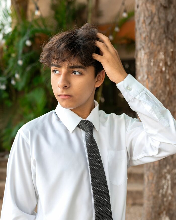 Teenage boy in a white shirt and black tie looking away. Represents a challenging airline seating lottery and seatmate stories.