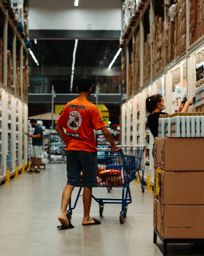 Man pushing a shopping cart in a warehouse, reflecting stereotypes about the US.