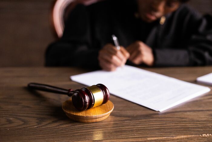 A gavel on a wooden table with a person writing in the background, representing shocking industry secrets.
