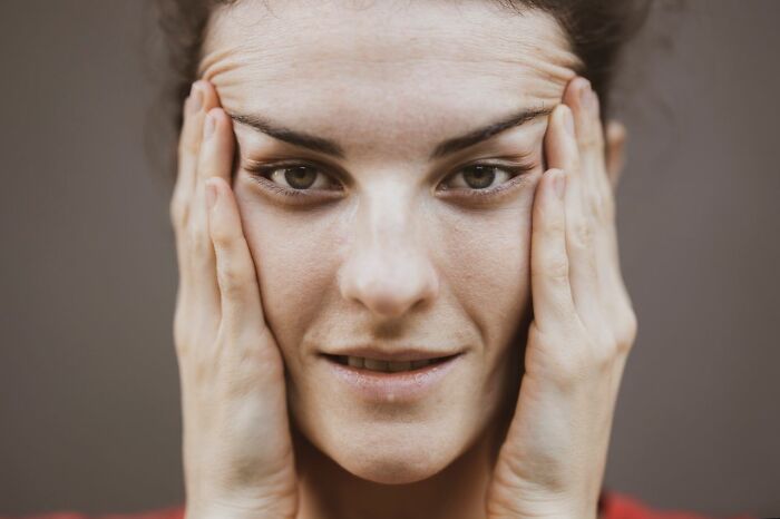 A woman touching her face, experiencing weirdest body changes in her 30s and 40s
