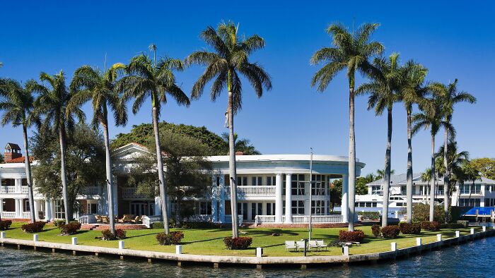 A luxurious waterfront mansion with tall palm trees, demonstrating how rich people live