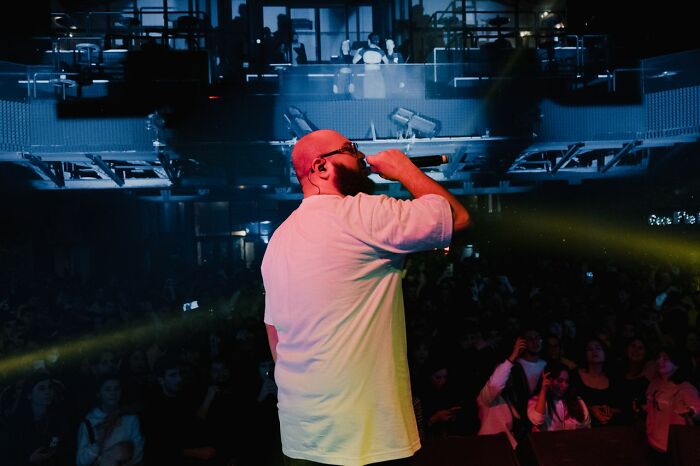 A person performing on stage with a mic, exploring simple joys people no longer take pleasure in.