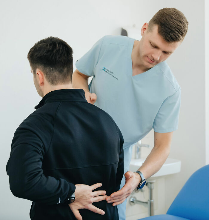 A doctor examining a man's back, focusing on health symptoms that terrify doctors.