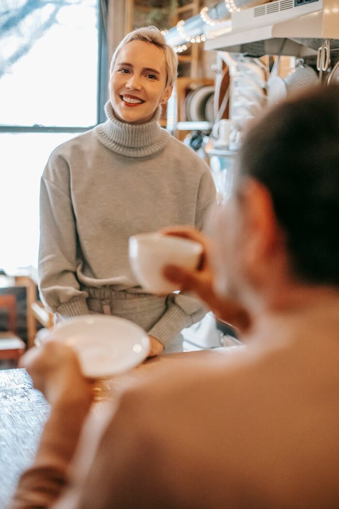 Smiling woman in gray turtleneck enjoying a simple joy, no longer taking pleasure in mainstream activities.