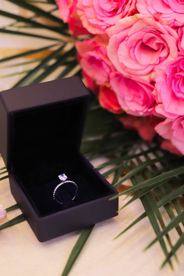 A diamond ring in an open box with pink roses, symbolizing a romantic dinner or celebration.