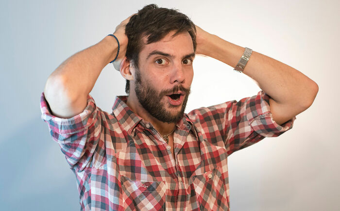 A man with a beard and hands on his head, looking shocked by lies men told them.
