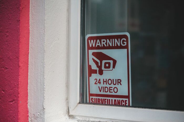 A warning sign for 24-hour video surveillance on a window, a safety tip for women living alone to protect themselves.