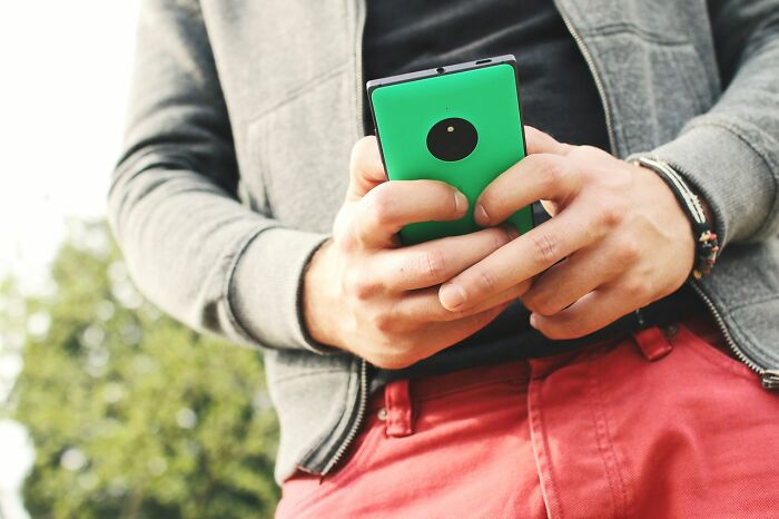 A person holding a green smartphone, contemplating simple joys ruined after becoming mainstream.