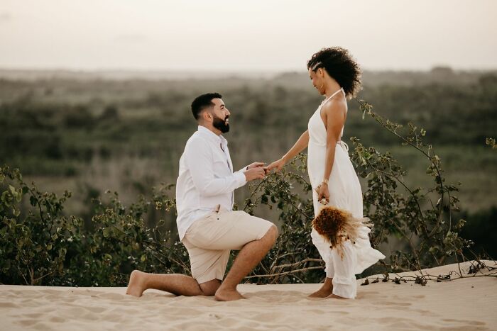 A man proposing to a woman on a sandy dune, reflecting a special dinner occasion.
