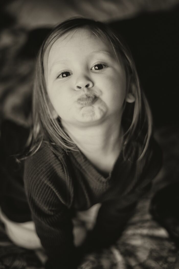 A black and white portrait of a young girl with pouting lips, capturing innocent childhood beliefs.