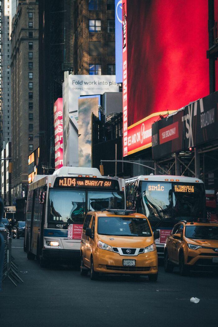 A busy New York City street scene with yellow taxis and buses, showcasing US stereotypes.