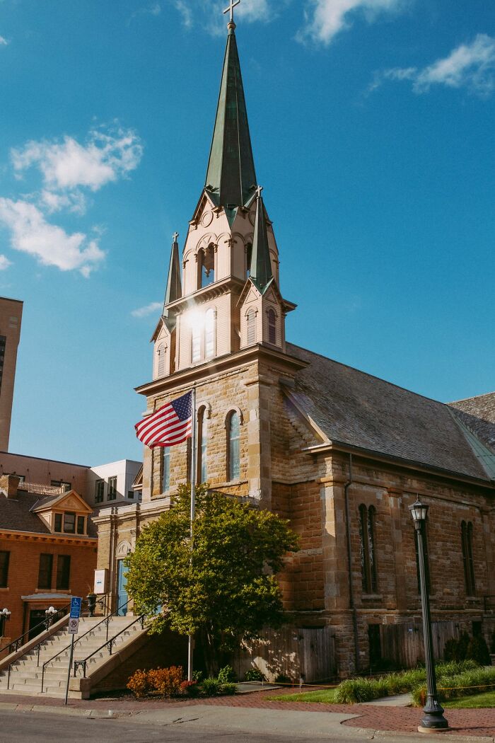 Historic US church with a tall steeple and an American flag, reflecting common stereotypes about the US architecture.