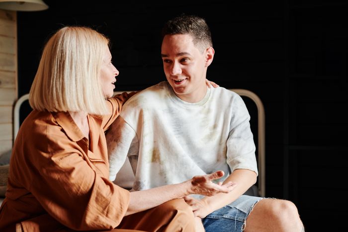 Mom's inheritance decision: A mom talks to her son about his inheritance while he smiles happily. Mom's inheritance decision: A mom talks to her son about his inheritance while he smiles happily.