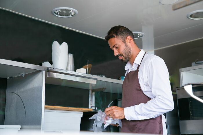 Restaurant worker wearing apron packaging food in kitchen