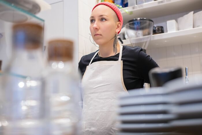 Restaurant worker in apron looking serious behind counter