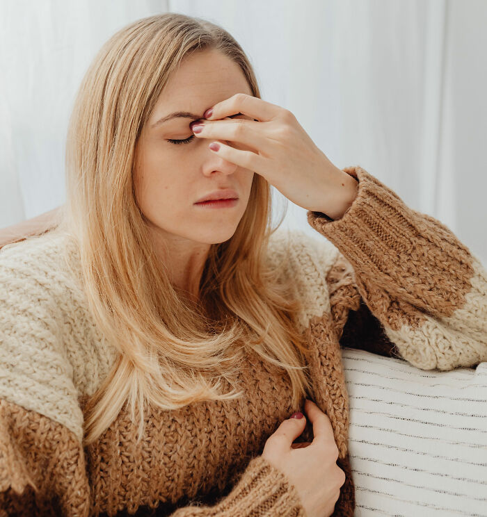 A woman with blonde hair holds her temples, looking distressed, representing innocent health symptoms that terrify doctors.
