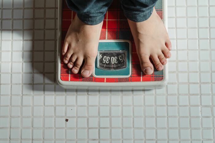 Feet on a bathroom scale, representing changes in weight, a common health symptom doctors monitor.