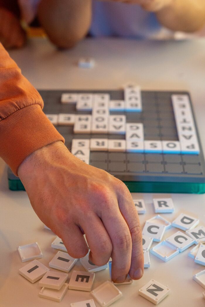 A close-up of a man's hand playing a board game, symbolizing dating red flags.