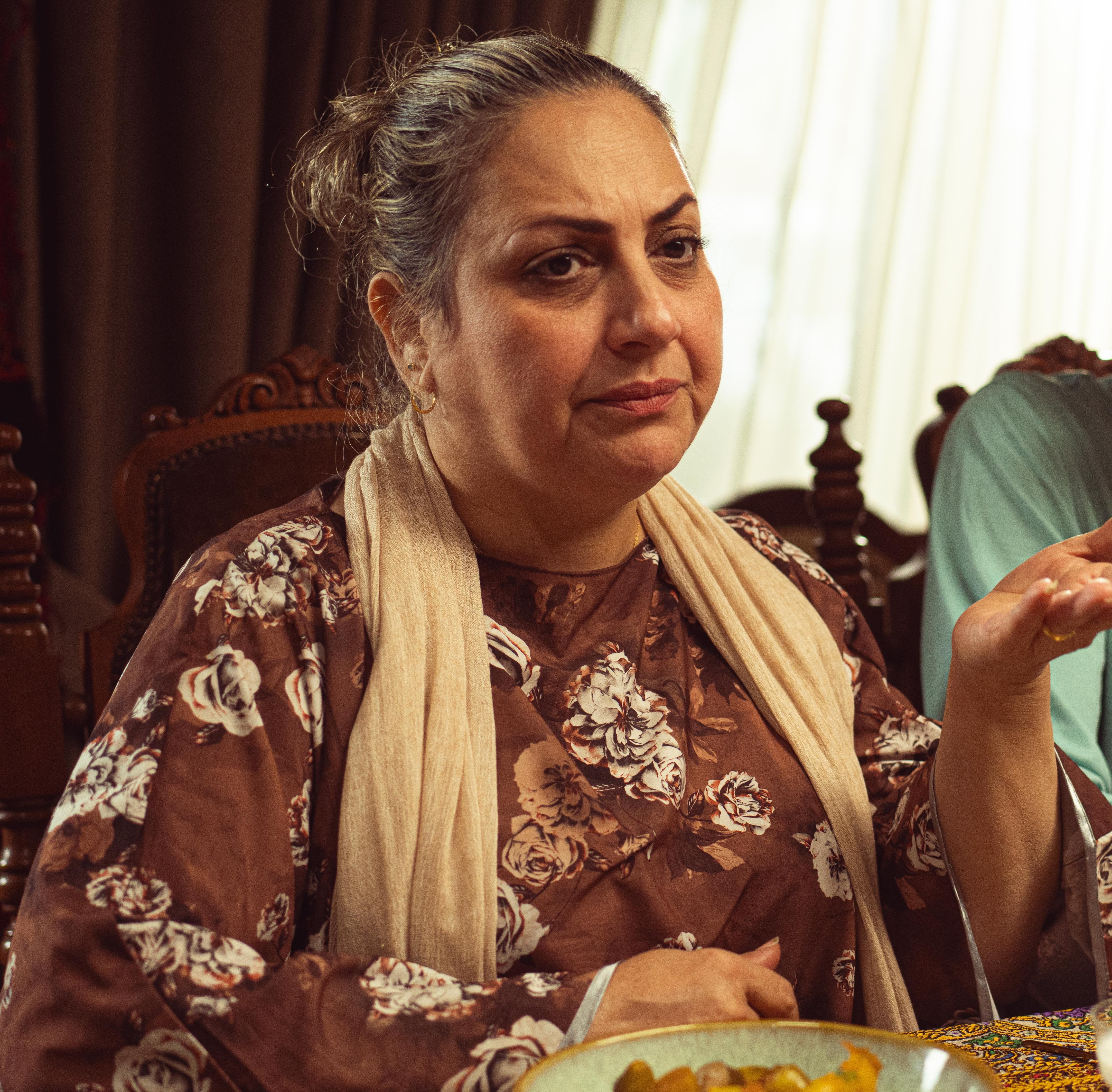 Middle-aged woman looking concerned with floral top and scarf Middle-aged woman looking concerned with floral top and scarf