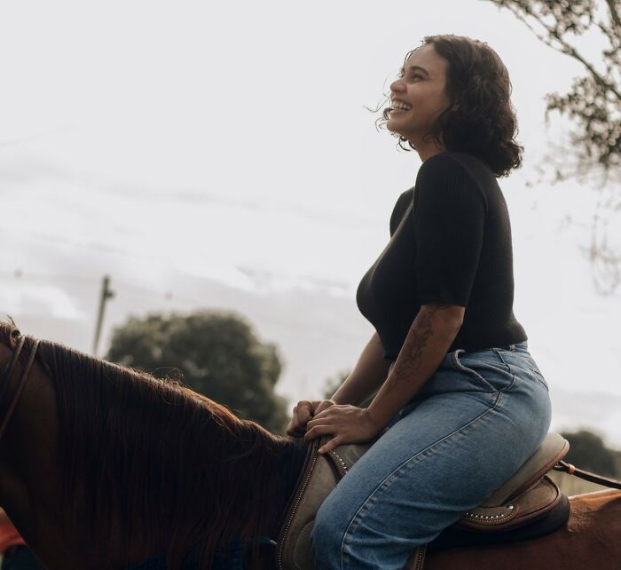 Smiling woman riding a horse, showcasing physical health and body changes in her 30s.