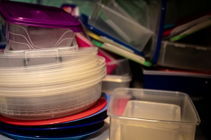 A pile of mismatched plastic food containers and lids, a funny description of an everyday inconvenience in kitchen organization.