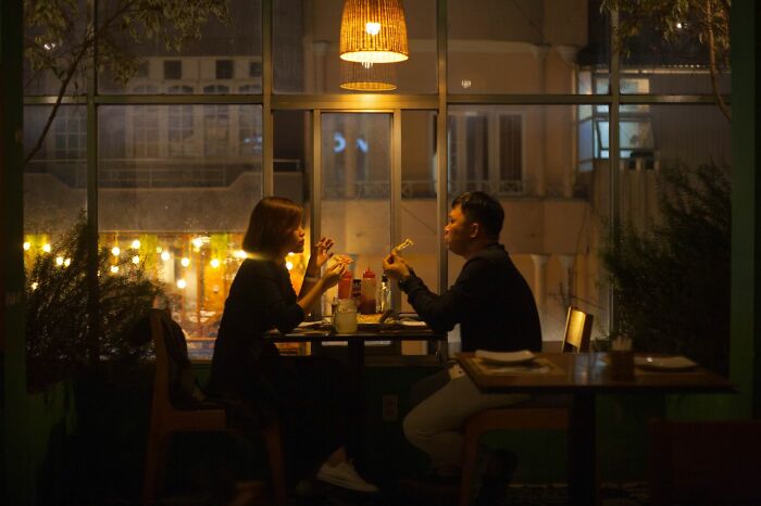 A couple enjoys a delicious dinner at a restaurant with warm lighting, suggesting a cozy dining experience.
