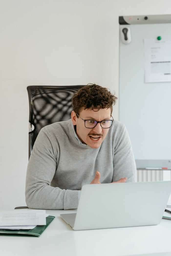 A man with glasses intently looking at his laptop, expressing frustration, perhaps from a loss of simple joys.