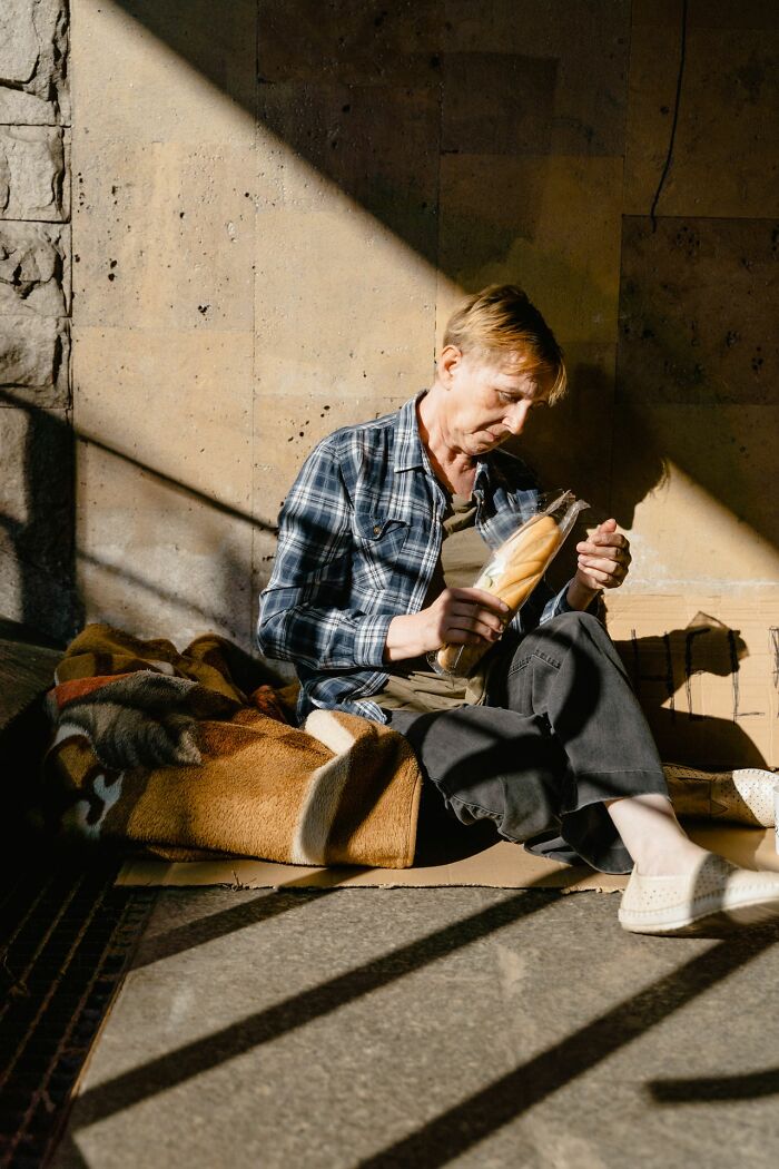 A person eating bread on the street, depicting a simple joy amidst hardship, potentially ruined by circumstances.