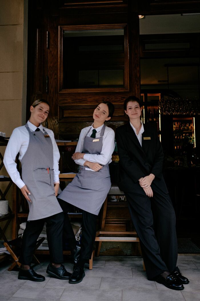Three restaurant staff members standing outside, ready to serve delicious dinner and hot tea.
