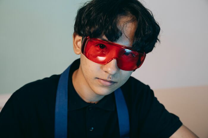 A young person wearing bright red safety goggles, representing laboratory or science-related scandals.