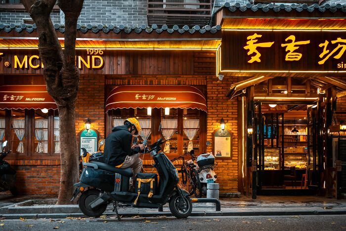 Delivery driver on scooter outside restaurant at dusk