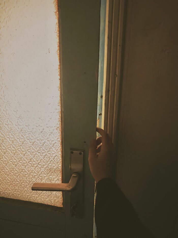 A hand reaching out to touch a doorframe next to a glass door. Safety tips for women living alone to protect themselves.