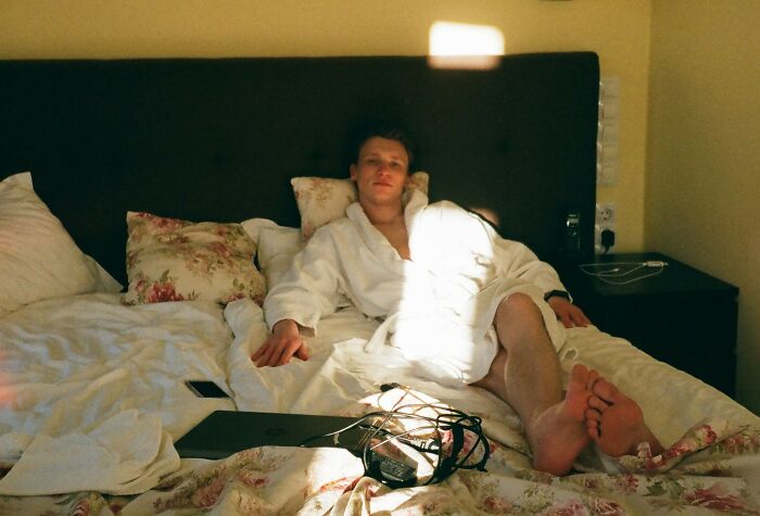 A man in a white robe relaxing on a bed, showing the comfort of rich people