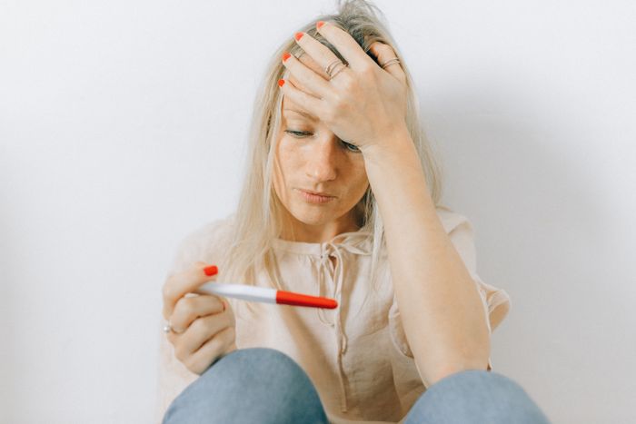 A distressed woman holds a positive pregnancy test, representing the situation after a wife cheats on her husband. A distressed woman holds a positive pregnancy test, representing the situation after a wife cheats on her husband.