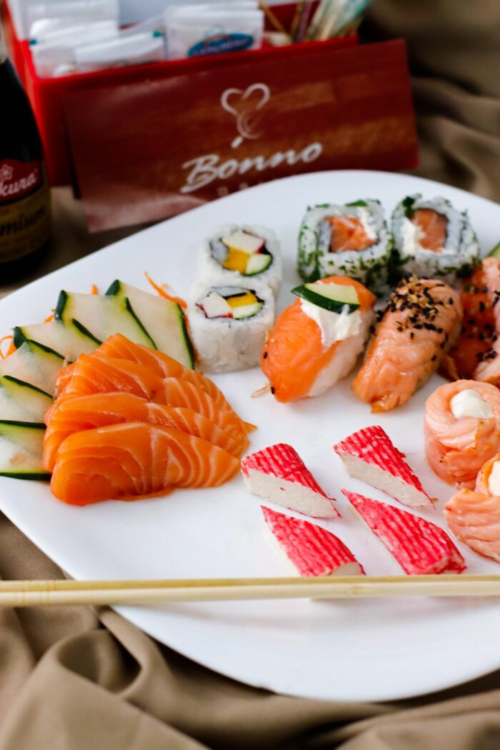 Plate of sushi, sashimi, and rolls, a delicious dinner option, possibly with hot tea nearby.