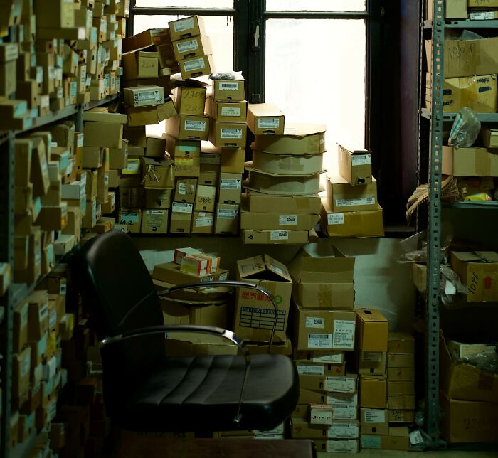 A messy storage room filled with boxes and a black office chair, suggesting hidden scandals