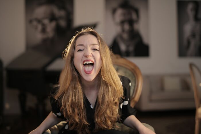A woman screaming with an open mouth, conveying shock or anger after people overheard something.