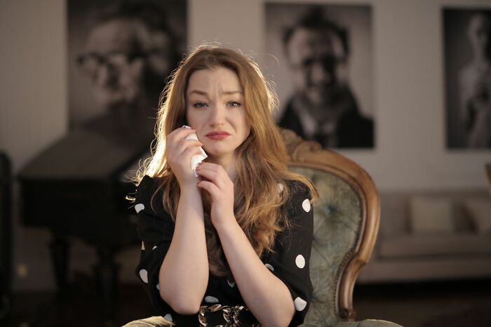 A sad woman crying with a tissue, perhaps after a difficult conversation, longing for comfort like dinner and hot tea.