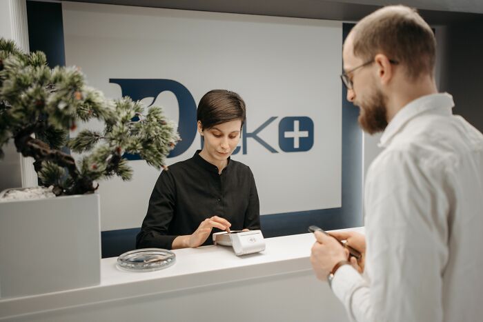 A receptionist assisting a customer at a clinic counter, relevant to scandals involving notable figures.