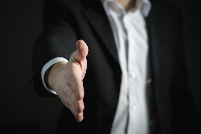 A businessman extending his hand for a handshake, representing corporate scandals