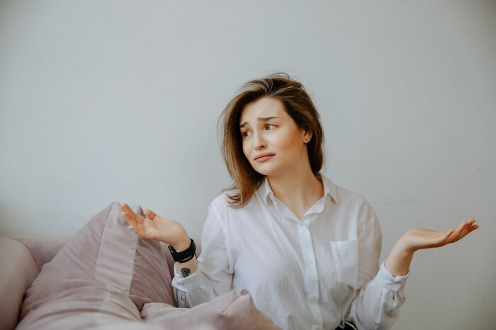 A perplexed woman is shrugging, feeling unsure and overwhelmed. This image shows women living alone to protect themselves with safety tips.
