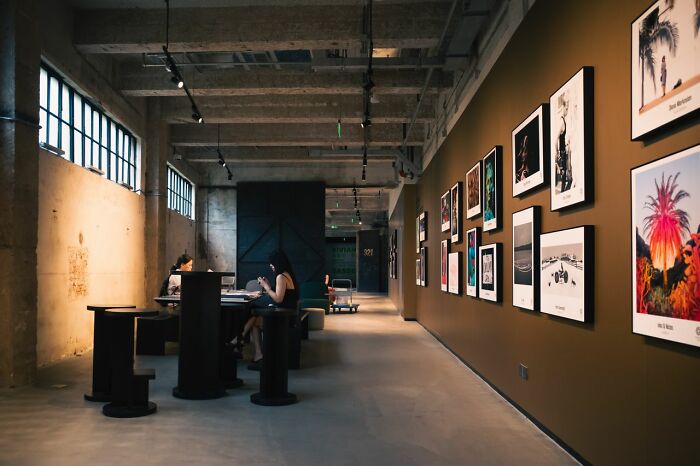 An office space with a long brown wall adorned with framed art, where simple joys can be found in daily work.