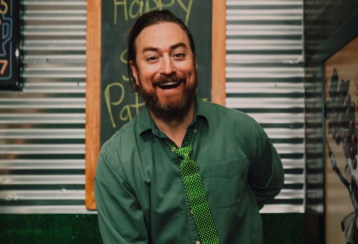 Smiling man with beard in green shirt at restaurant