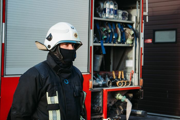 A therapist in a protective helmet and gear, standing next to a fire truck, reflecting on encountering a sociopath.