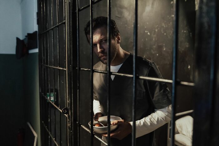 A man in a prison cell holding a bowl, highlighting how therapists identify a sociopath.